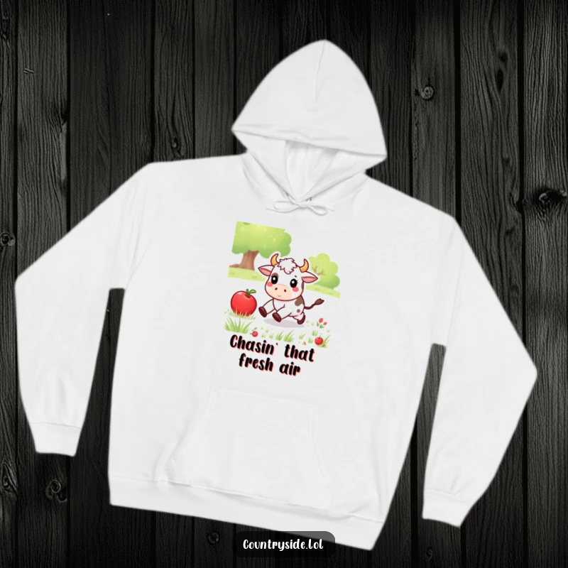 Funny Kawaii cow character excitedly chasing an apple through a meadow, perfect for a cozy and humorous hoodie.